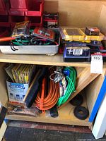 Shelf with DeWalt bit cases, sandpaper, cords, bins, broom head and wire