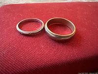 Both wedding bands side by side on red surface