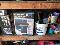 Boxed Flowtron insect killer, boxed Slime Air Station, bucket of garden tools, candles visible