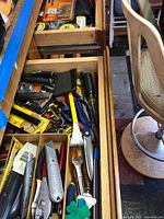 Drawer containing utility knives, hammer, pliers, screwdrivers, tape measure and packaged drill bits