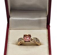 Ring in box showing center pink stone and clear accents