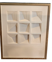 Front view of framed abstract paper relief artwork showing nine square panels with geometric linear patterns and metallic frame