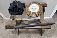 Group view of bayonet, tribal knife, barometer, binoculars on wooden stand
