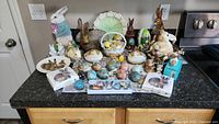 Wide view of entire assortment on countertop showing rabbit figurines, decorative eggs, packaged cookie cutters and napkins