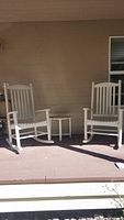 Two white rocking chairs and small round table on porch