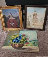Group shot of three artworks: framed oil portrait, framed mixed-media figure, unframed floral canvas