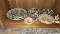 Six baskets, cloth doll, pottery storyteller displayed on shelf