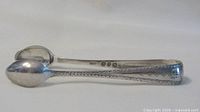 Side view of sterling silver tongs showing shape and engraving