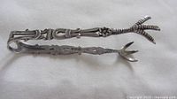 Full view of ornate sterling silver claw tongs
