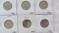 Front of six Canada quarters in flips showing dates 1986-1991