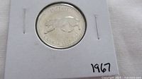 Bobcat reverse of 1967 Canadian quarter in cardboard flip