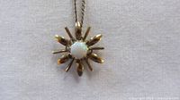 Front view of gold-filled sunburst pendant with opal center on chain
