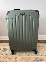 Front view of sage green hard-shell Kenneth Cole Reaction suitcase with spinner wheels