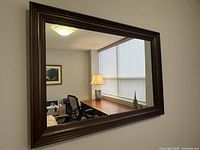 Front view of rectangular mirror with walnut wood frame mounted on wall
