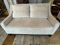 Front view of cream velvet two-seater sofa showing cushions and teak base