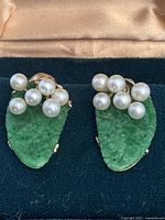 Front view showing carved jade leaves, pearl clusters, and gold settings