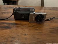 Canon Snappy EZ film camera and Canon PowerShot SD750 digital camera on table