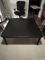 Front angled view of black square coffee table showing full top and legs