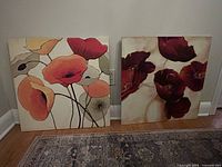 Two square floral canvas prints leaning against wall