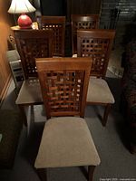 Front view of five matching wood dining chairs with lattice backs and tan seats