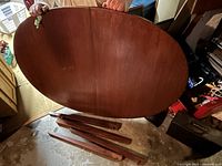 Tabletop held vertically showing oval shape and wood finish