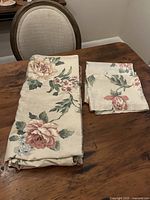 Beige floral duvet cover folded alongside matching shams on wooden table