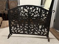 Front view of wrought iron fireplace screen showing scroll design and overall condition