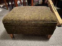 Greenish upholstered ottoman with wooden legs, full view
