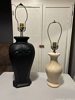Black and cream lamp bases with harps and sockets on table