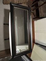 Front view of rectangular mirror showing black frame and gold bead trim