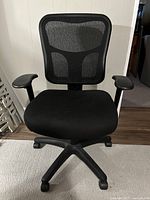 Front view of black mesh office chair showing seat, backrest, armrests and wheeled base
