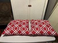 Both red geometric cushions side by side on table