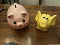 Pink pig and yellow elephant piggy banks on table