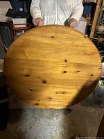Front view of round pine table top held vertically