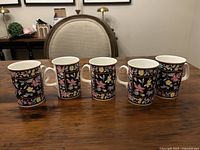 Five Royal Doulton Festival Time bone china mugs displayed upright side by side