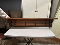 Front view of wooden slat shelf showing five hooks and side brackets