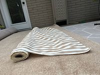Bolt of tan and white striped fabric rolled out on carpeting