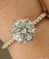 Close-up of ring on finger showing center stone and pavé accent stones