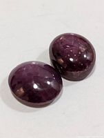 Pair of oval cabochon star rubies showing color and asterism