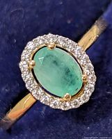 Close view of silver ring with green oval stone and clear CZ halo