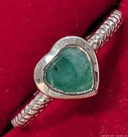 Front view of silver ring showing heart emerald and rope shank