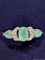 Front view showing oval centre emerald, two round side emeralds and accent stones