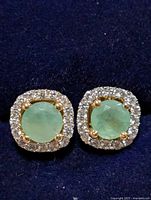 front view of both emerald halo studs on blue background