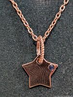 Close-up of star pendant showing sapphire accent and chain loop