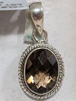 Front view of silver pendant showing oval faceted smokey quartz and rope bezel