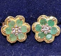Front view of both floral emerald stud earrings in case