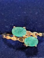 Top view showing two oval emerald stones on wavy band