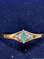 Front view of sterling silver ring with marquise emerald and two clear accent stones