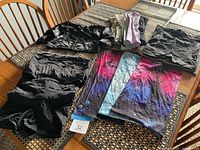 All garments laid out on table: abdominal wrap, compression shorts, satin top, three coloured compression underwear, sun sleeves