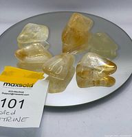 Six tumbled citrine stones on round mirror with lot tag visible